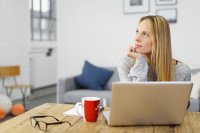 Working female looking distractedly away from her laptop