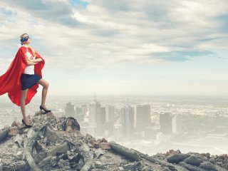 Individual in super hero cap standing on top of a mountain