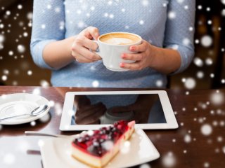 Woman with coffee at laptop with snow falling